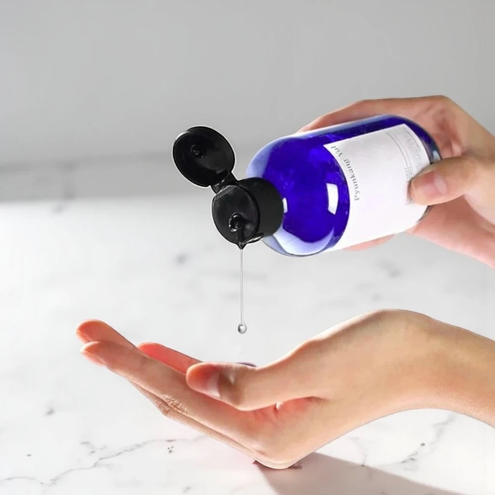 Skin TOGO Pyunkang Yul Essence Toner being poured from a blue bottle into a hand for skincare application