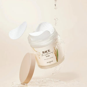 Skin TOGO SKINFOOD Rice Brightening Pads in a jar with water splashes and floating cotton pads for skin exfoliation