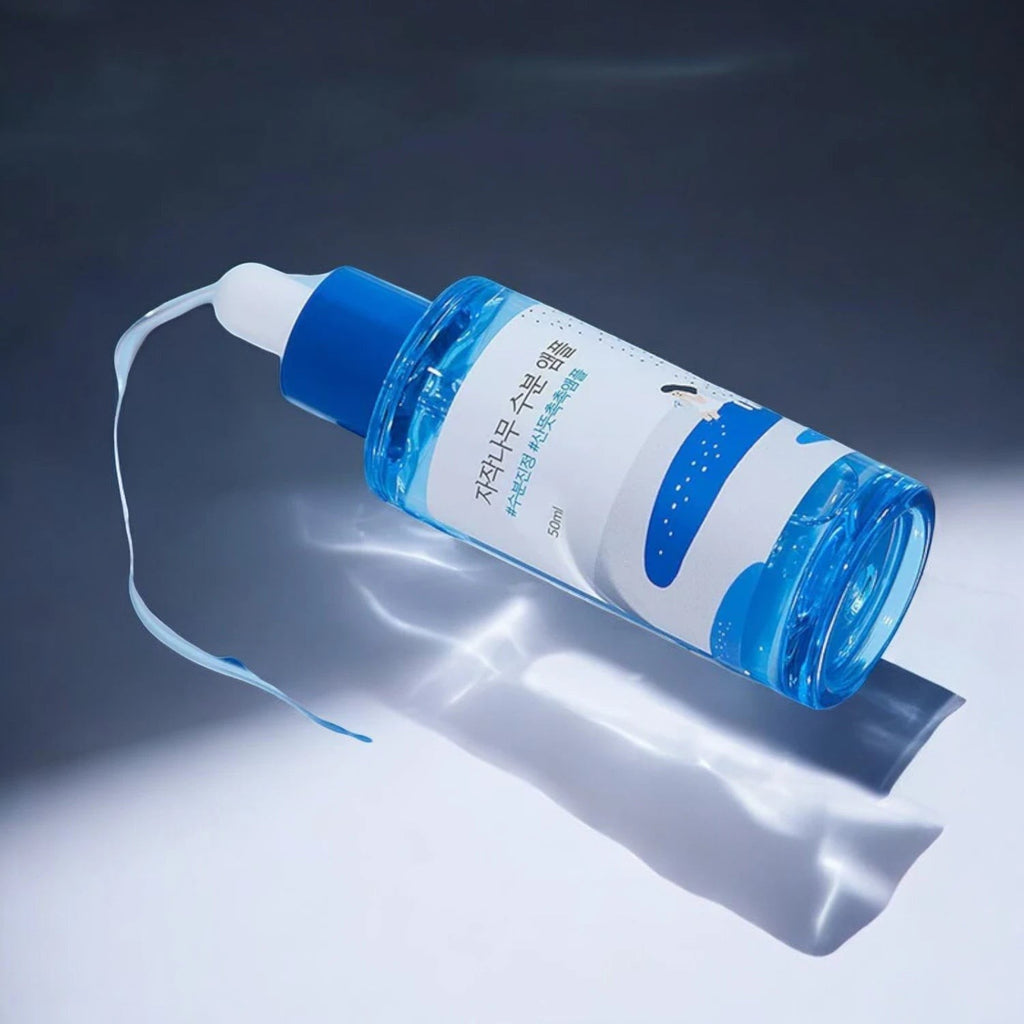 Skin TOGO Round Lab Birch Juice Moisturizing Ampoule in a blue translucent bottle with a dropper on a white surface.