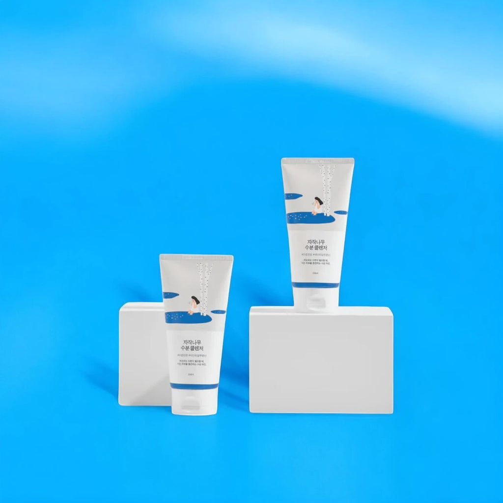 Skin TOGO Round Lab Birch Juice Moisturizing Cleanser tubes displayed on white blocks against a bright blue background.