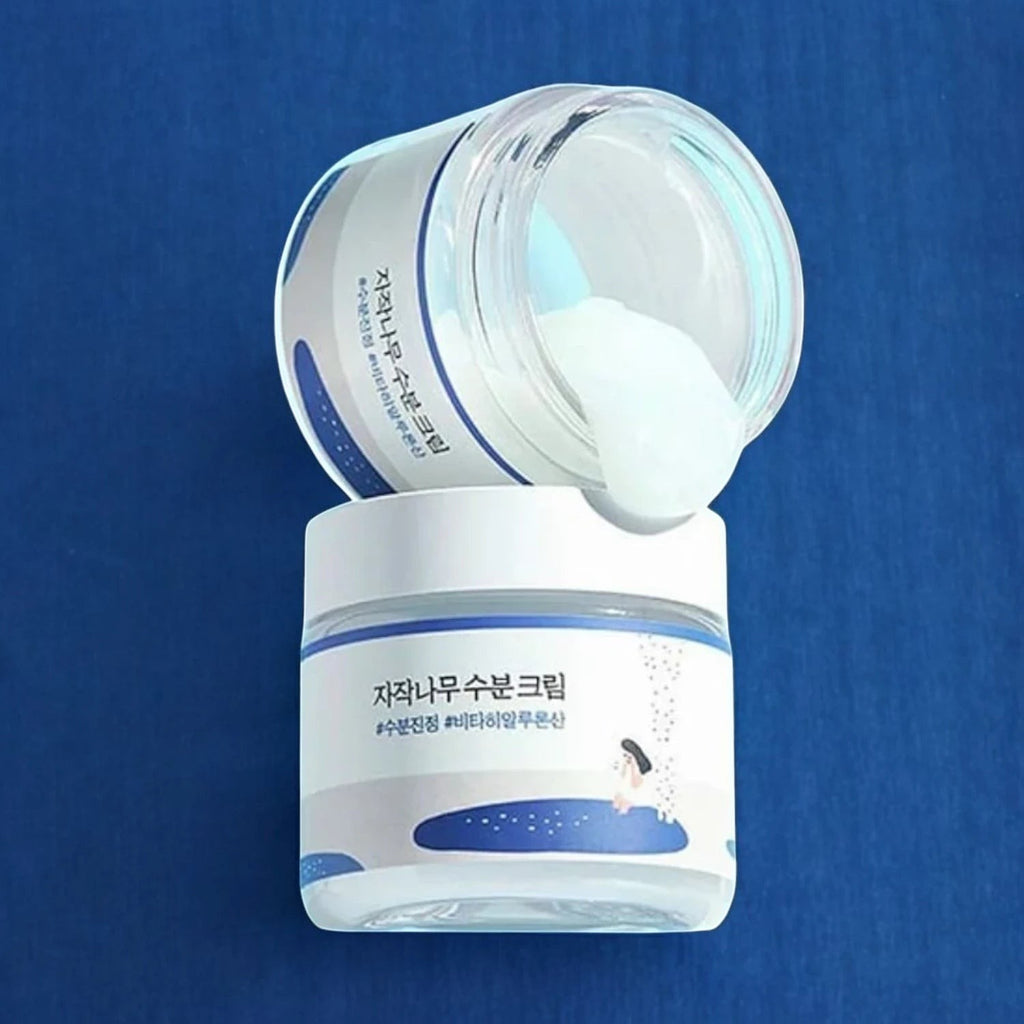 Skin TOGO Round Lab Birch Juice Moisturizing Cream in a glass jar with a white lid, showing a rich white texture.
