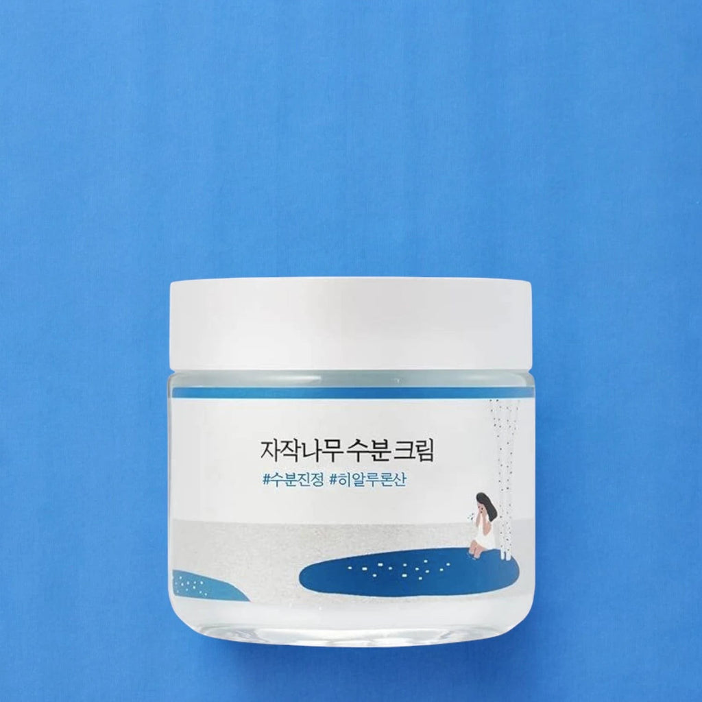 Skin TOGO Round Lab Birch Juice Moisturizing Cream in a white jar with blue label on a blue background.