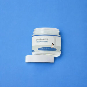 Skin TOGO Round Lab Birch Juice Moisturizing Cream in a clear jar with white lid on a blue background