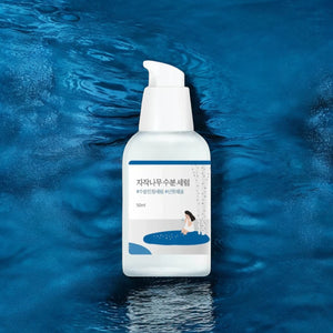 Skin TOGO Round Lab Birch Juice Moisturizing Serum in a white pump bottle against a deep blue water background.