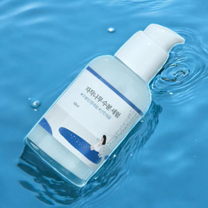 Skin TOGO Round Lab Birch Juice Moisturizing Serum bottle floating in clear blue water for deep skin hydration.