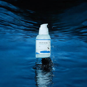 Skin TOGO Round Lab Birch Juice Moisturizing Serum bottle floating above dark blue water with refreshing splashes