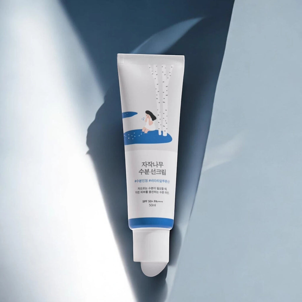 Skin TOGO Round Lab Birch Juice Moisturizing Sun Cream in a white tube with blue accents and birch tree illustration.