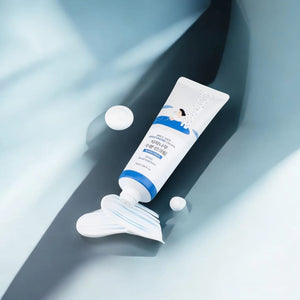 Skin TOGO Round Lab Birch Juice Moisturizing Sun Cream tube with creamy texture on a blue background