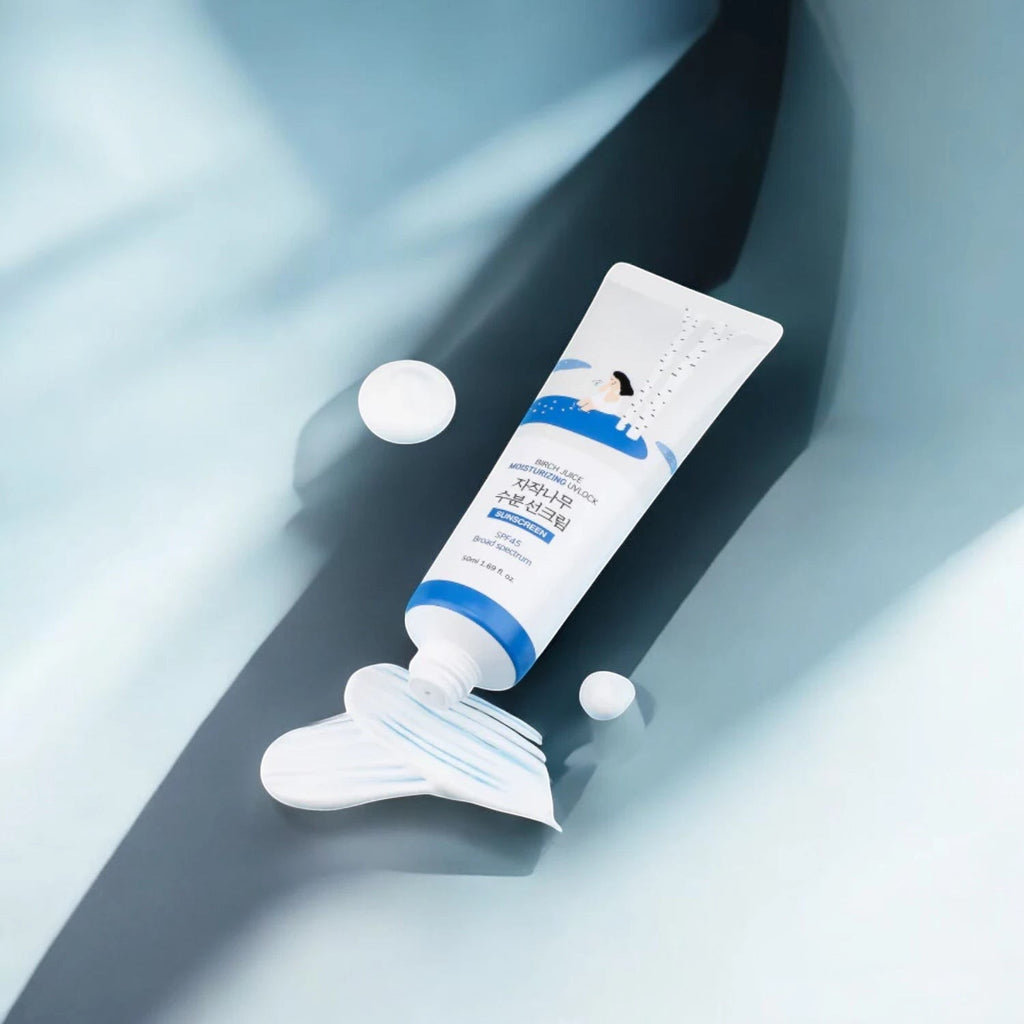 Skin TOGO Round Lab Birch Juice Moisturizing Sun Cream tube with creamy texture on a blue background