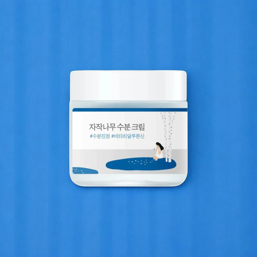 Skin TOGO Round Lab Birch Juice Moisturizing Cream in a white jar against a vibrant blue background.