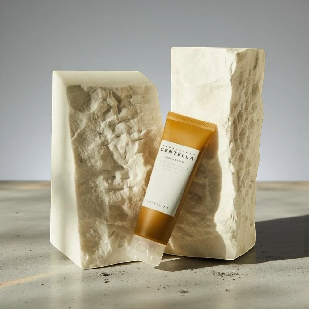 Skin TOGO SKIN1004 Madagascar Centella Ampoule Foam cleanser in a tube displayed between two textured stone blocks.