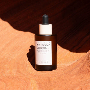 Skin TOGO SKIN1004 Madagascar Centella Probio-Cica Intensive Ampoule in a brown glass bottle on textured orange sand.