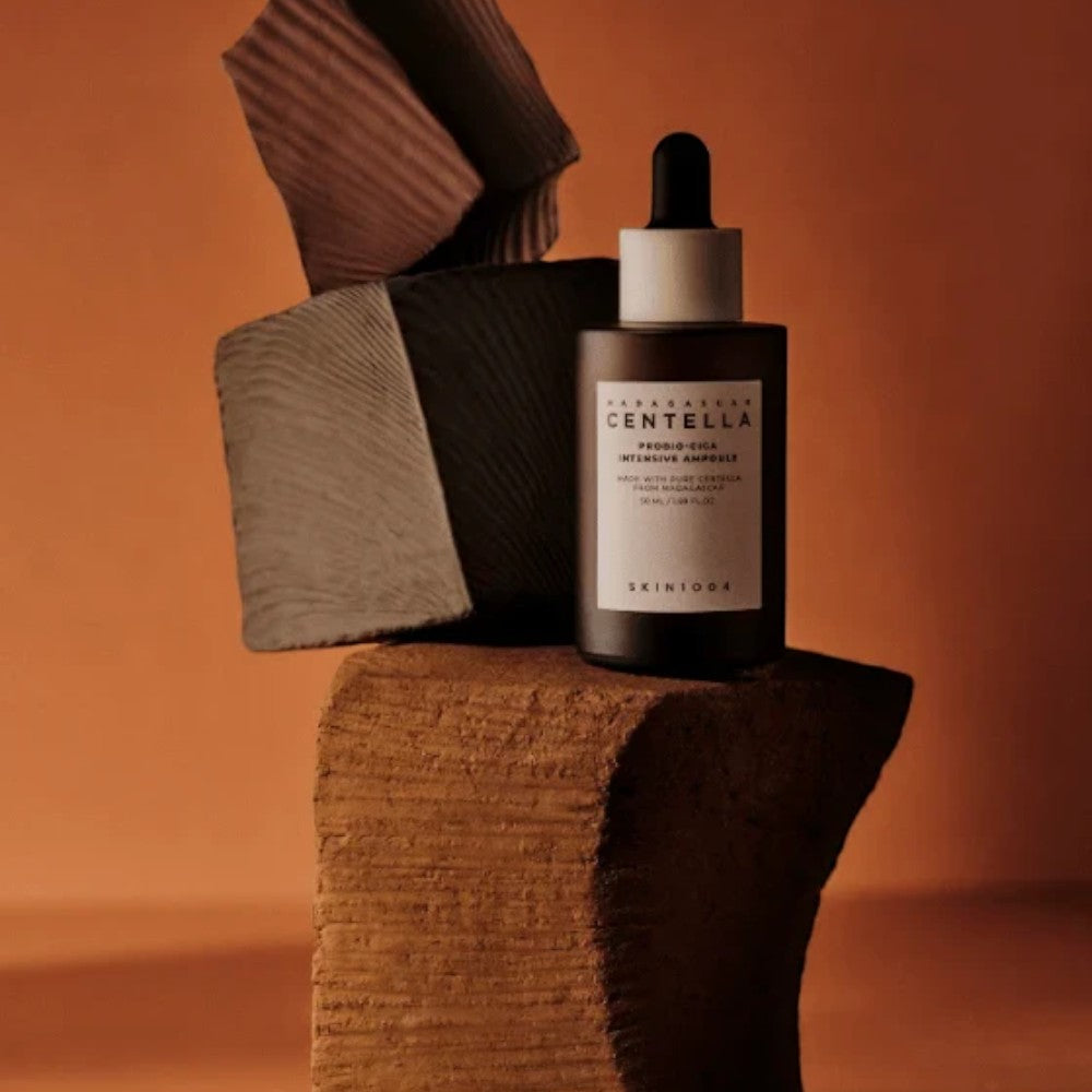 Skin TOGO SKIN1004 Madagascar Centella Probio-Cica Intensive Ampoule bottle on a stone pedestal in a warm studio.