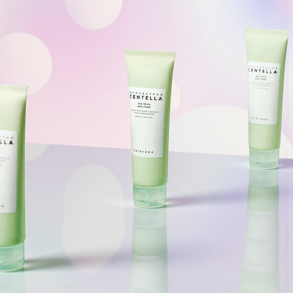 Skin TOGO SKIN1004 Madagascar Centella Tea-Trica BHA Foam cleanser tubes on a reflective surface with bokeh background