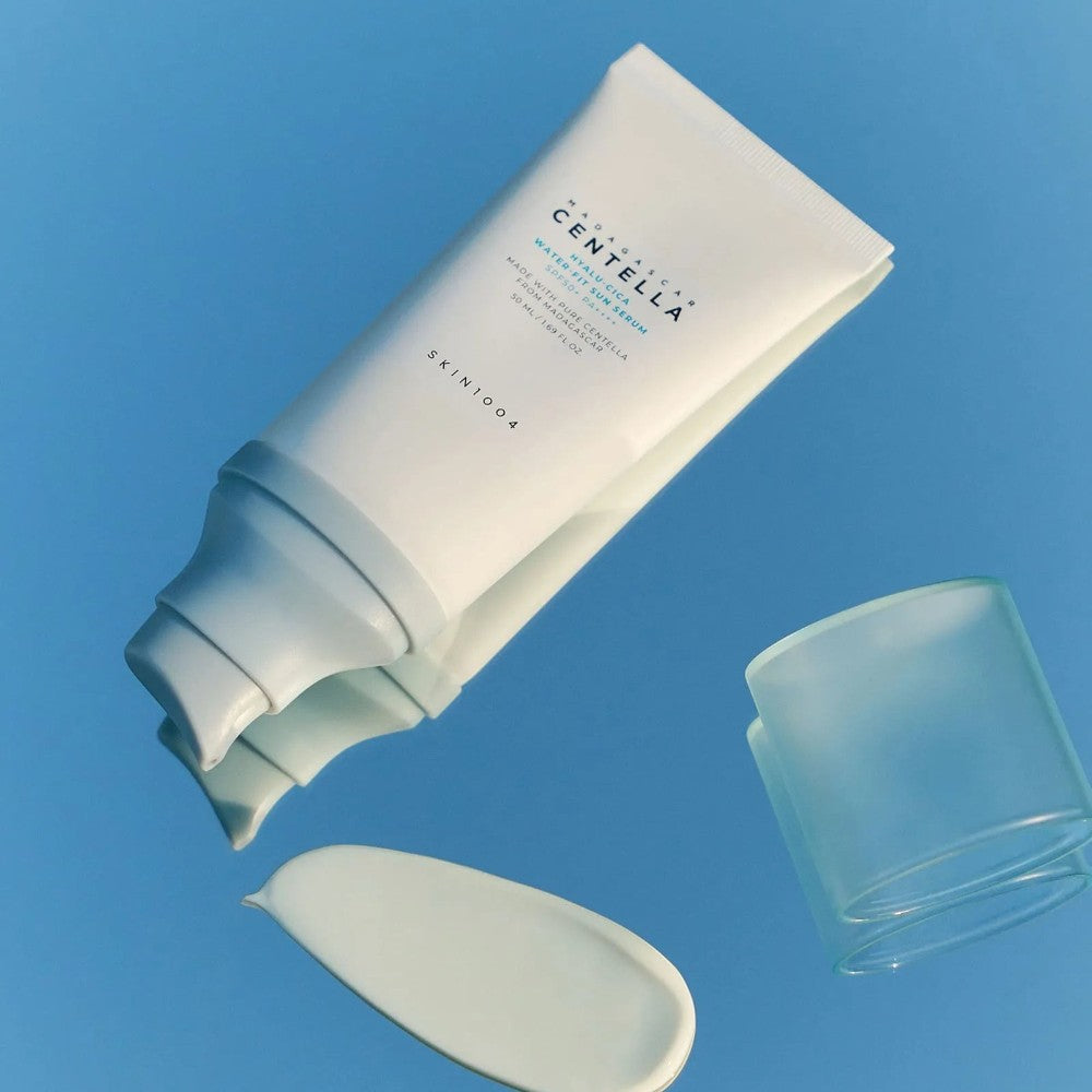 Skin TOGO SKIN1004 Madagascar Centella Hyalu-Cica Water-Fit Sun Serum tube with dispensed cream on a blue surface.