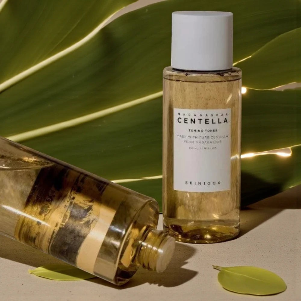 Skin TOGO SKIN1004 Madagascar Centella Toning Toner in a clear bottle with white cap, set against a large green leaf.