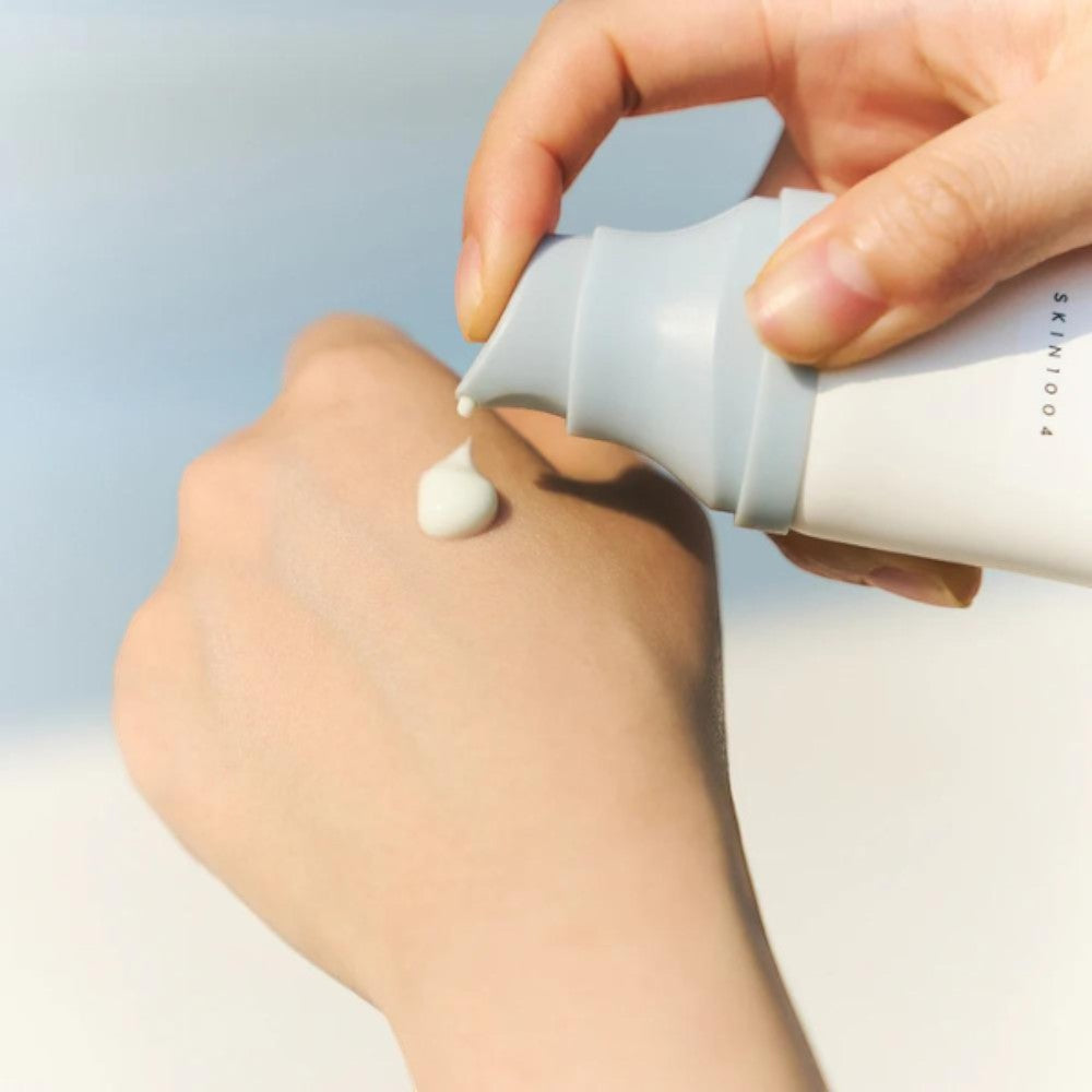 Skin TOGO SKIN1004 Madagascar Centella Hyalu-Cica Water-Fit Sun Serum being applied to a hand, showing light texture.