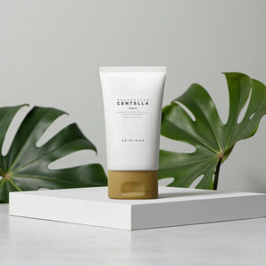 Skin TOGO SKIN1004 Madagascar Centella Cream in a white tube with a gold cap, displayed on a white pedestal.