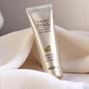 Skin TOGO Skin79 Golden Snail Intensive Eye Cream in a gold tube resting on soft white fabric.