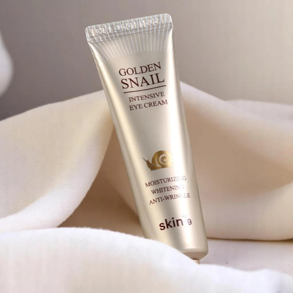 Skin TOGO Skin79 Golden Snail Intensive Eye Cream in a gold tube resting on soft white fabric.