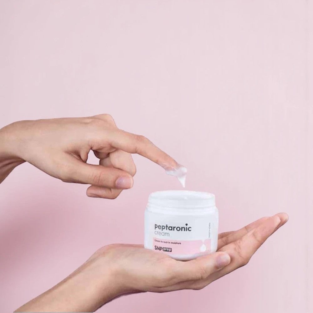Skin TOGO SNP Prep Peptaronic anti-aging cream jar held in hand with a dab of white moisturizer on a finger
