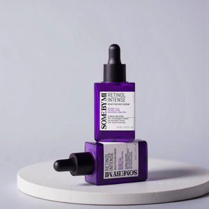 Skin TOGO SOME BY MI Retinol Intense Reactivating Serum in purple glass dropper bottles on a white pedestal.