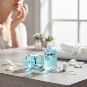 Skin TOGO Torriden DIVE-IN hyaluronic acid serum bottles on a vanity with petals and a blurred woman in the background