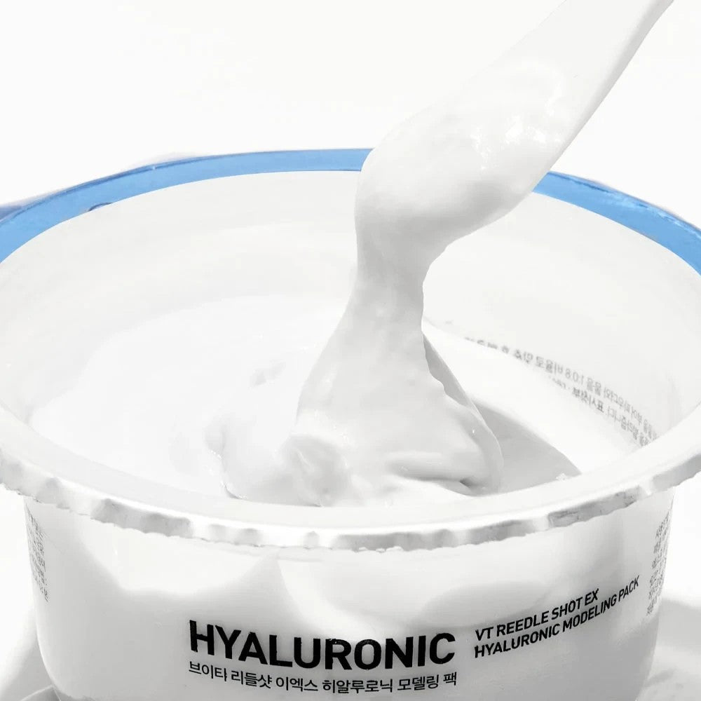 Skin TOGO VT Cosmetics Reedle Shot EX Hyaluronic Modeling Pack with creamy white texture being lifted by a spatula