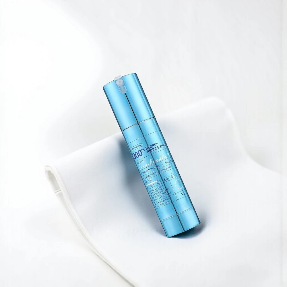 Skin TOGO VT Cosmetics Hydrop Reedle Shot 300hL hydrating serum in a metallic blue pump bottle on white fabric.